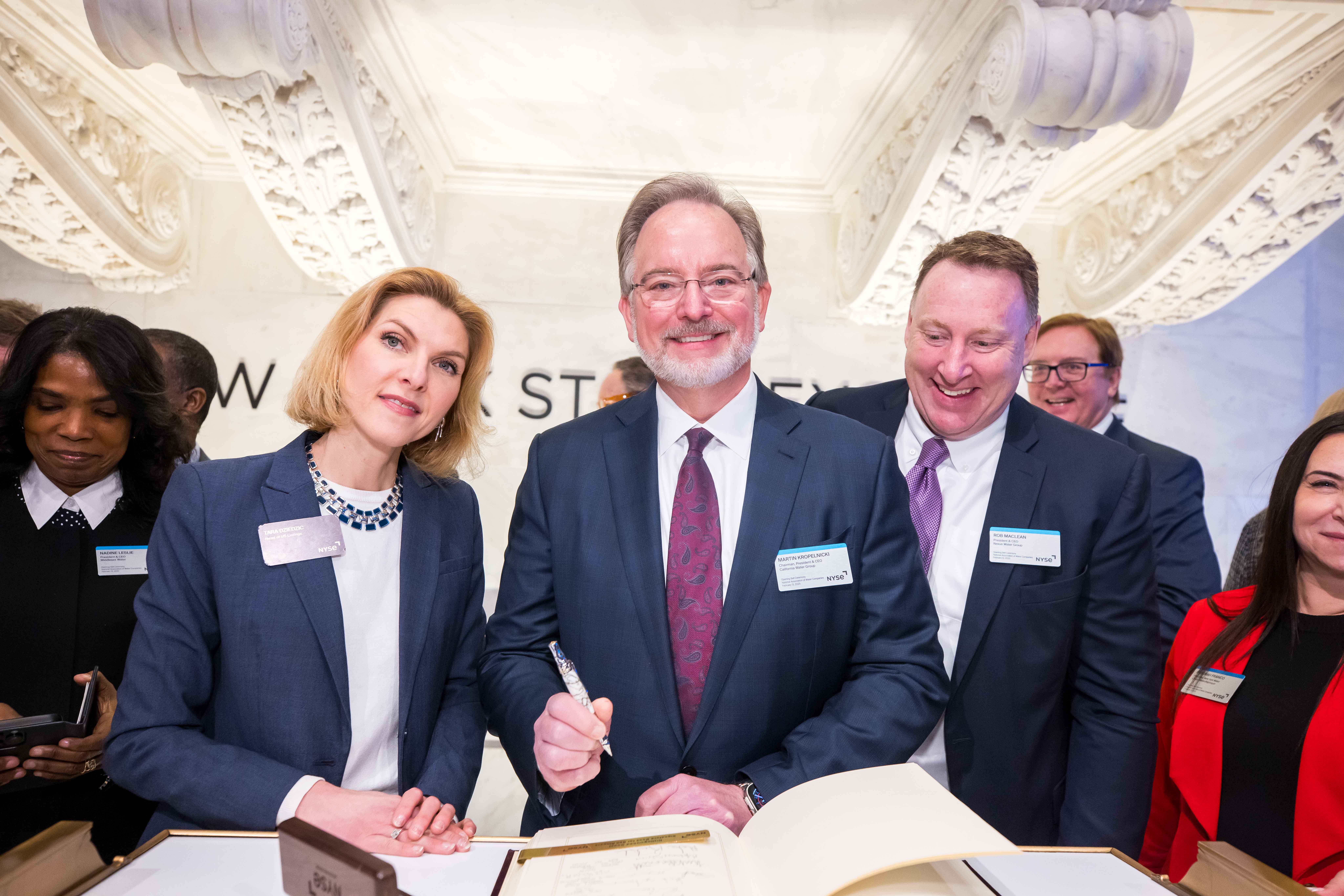 Martin A. Kropelnicki and two other members of NWAC stand behind a book. Martin has a pen in his hand. 